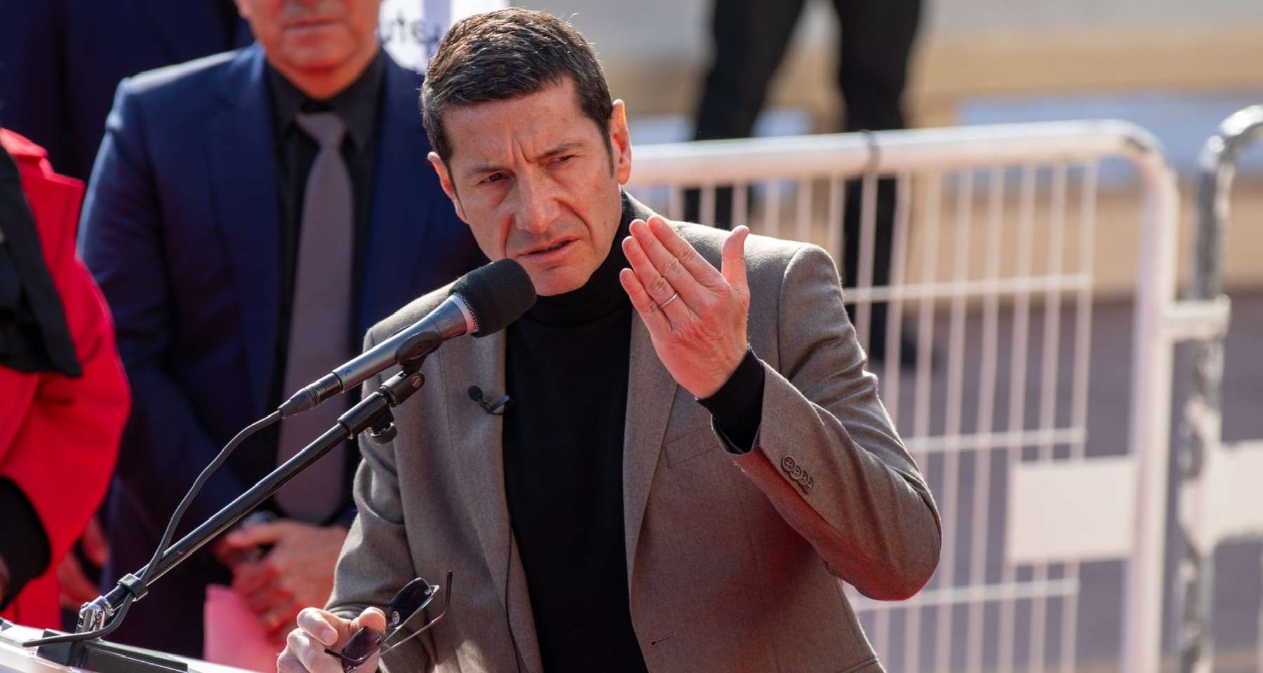 David Lisnard en costume gris, adressant un discours, devant un pupitre avec micro